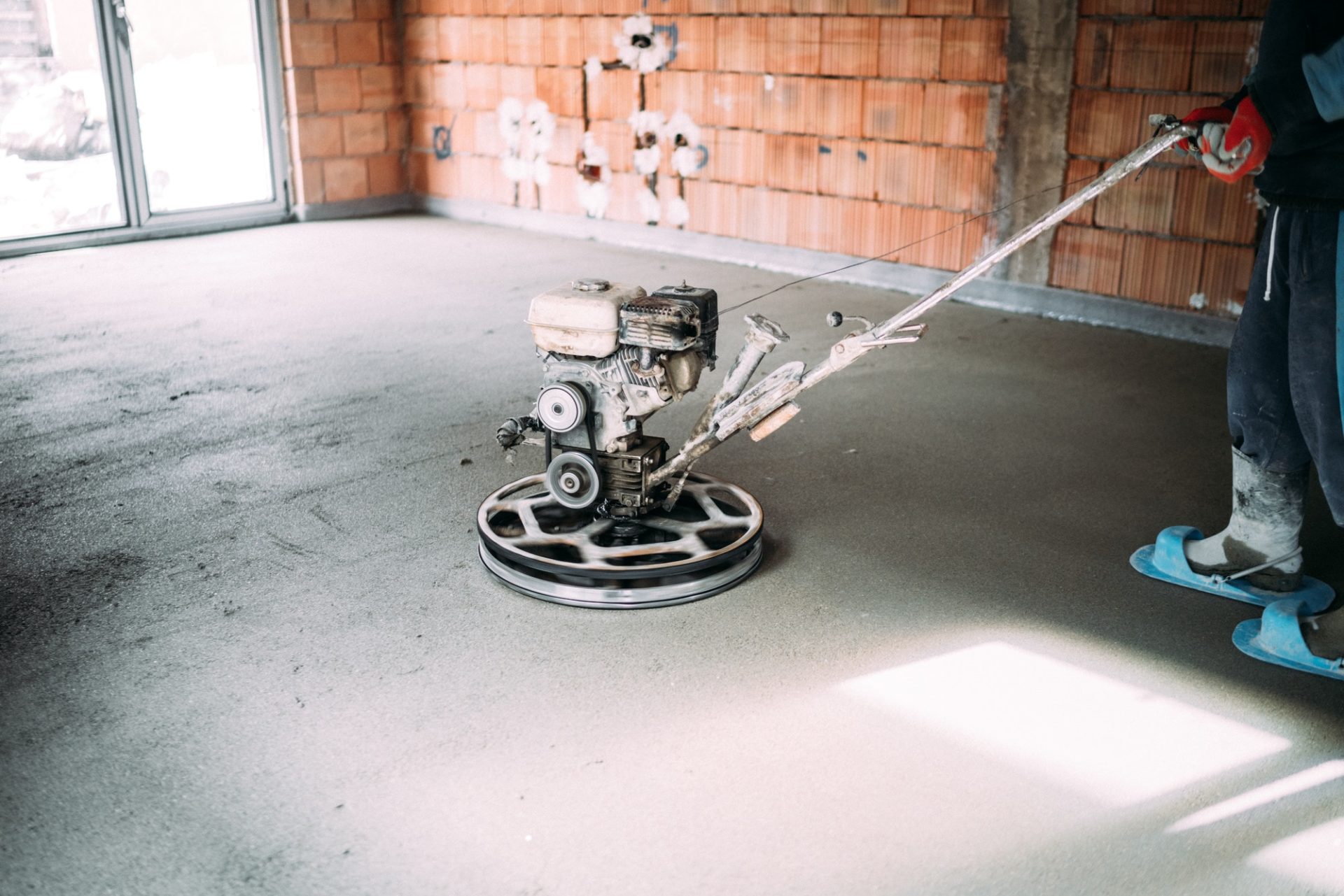 industrial worker finishes concrete screed with trowel machine